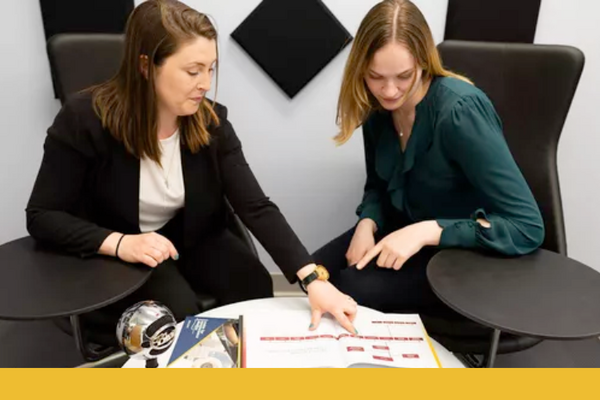 An advisor and student look at a course guide book together