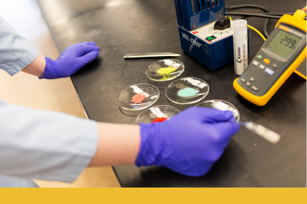 A pair of hands wearing gloves using a test instrument to measure chemicals