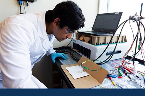 Student wearing protective goggles and gloves performs chemistry experiment