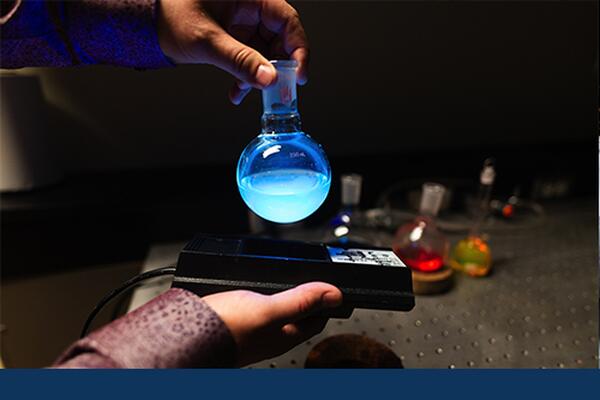 Pair of hands holding a vial of blue liquid