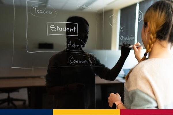 image of graduate student writing on a glass whiteboard