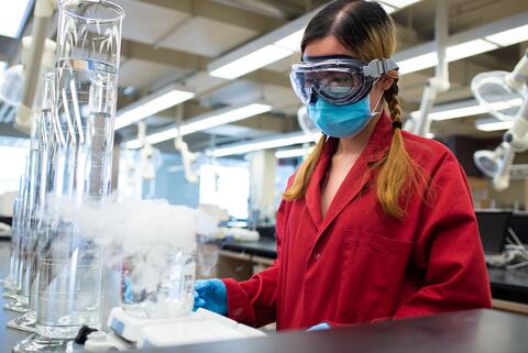 Student watches a Chemistry experiment taking place as smoke rises from a flask