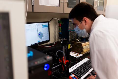 Student wearing a face mask performs lab work using a computer