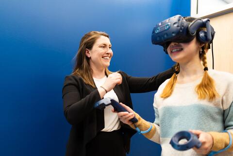 Faculty member adjusts the headset on a graduate student being used as part of an experiment on virtual chemical education