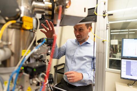 Faculty member demonstrates a piece of research equipment used for chemistry experiments