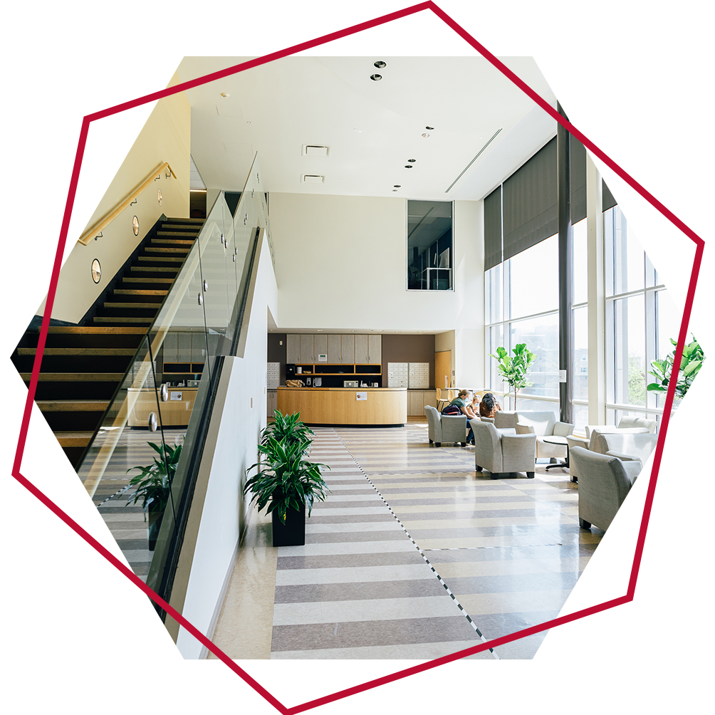 Lobby at Chernoff Hall with staircase leading upwards on the left, students sitting in chairs on main floor