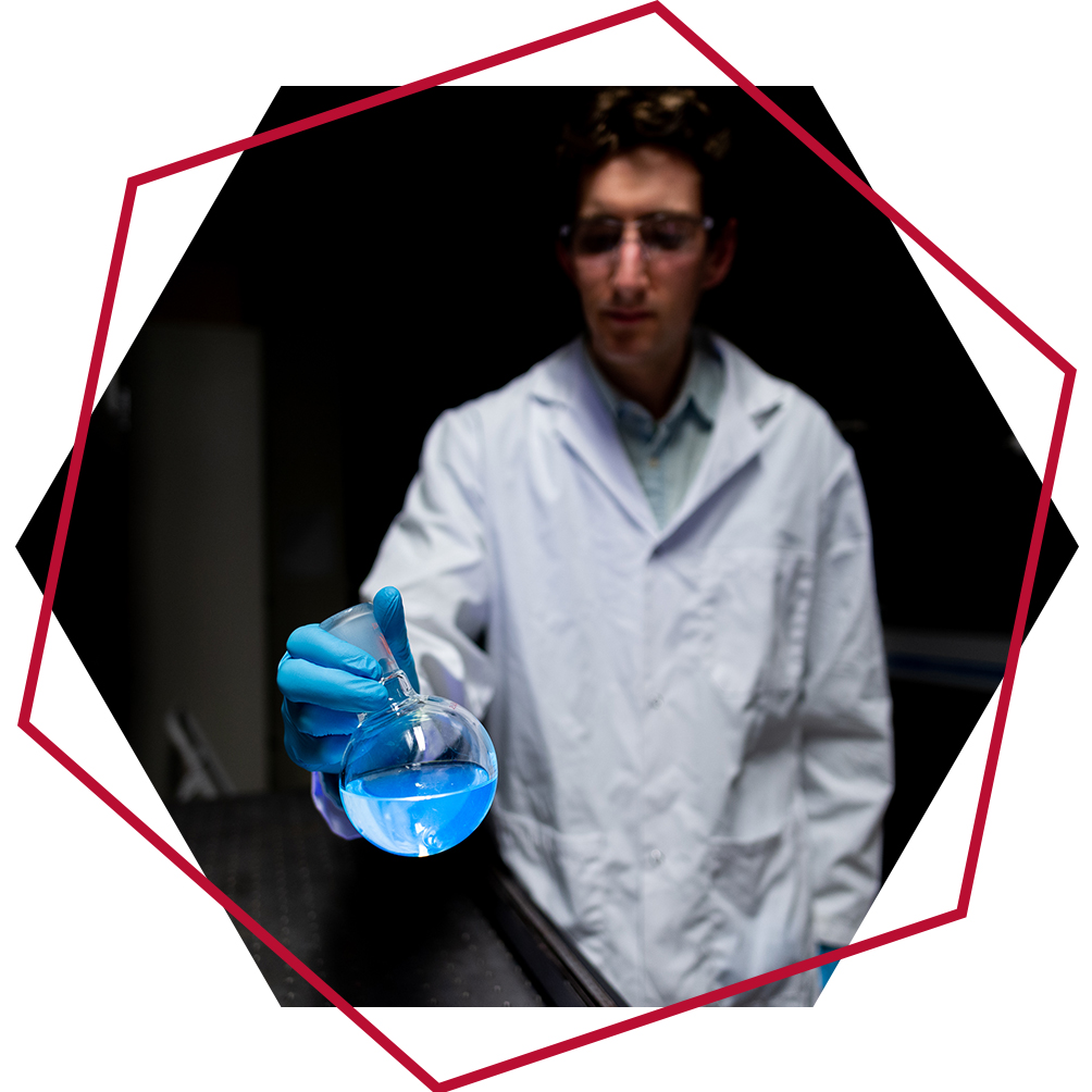 Graduate student holding a flask filled with blue liquid